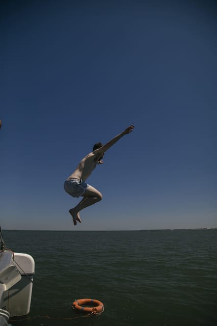 Lisbon: Catamaran Boat Party with Music, Open Bar & Dives - The 25 de Abril Bridge from the River